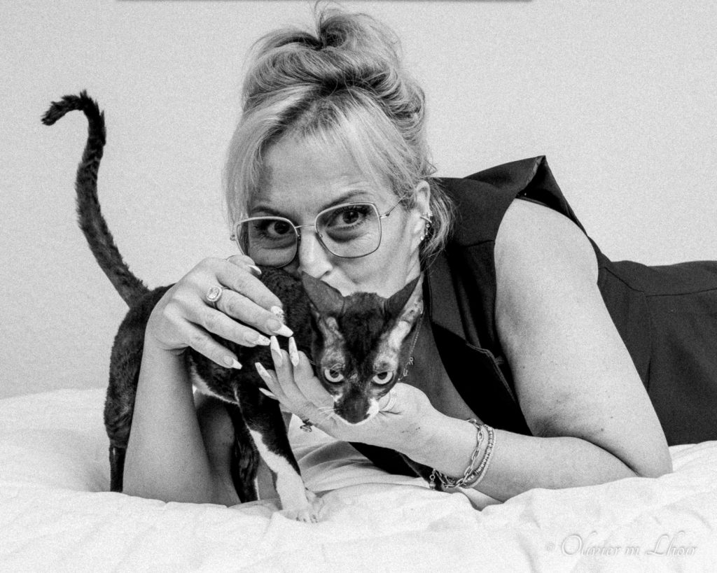 Portrait féminin en noir et blanc d'un Cornish Rex en studio.