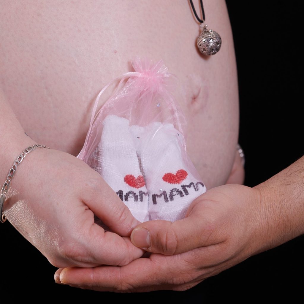 ventre rond enceinte avec chausson dans les mains