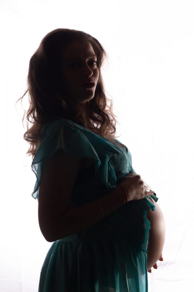 une femme de profil enceinte sur fond blanc