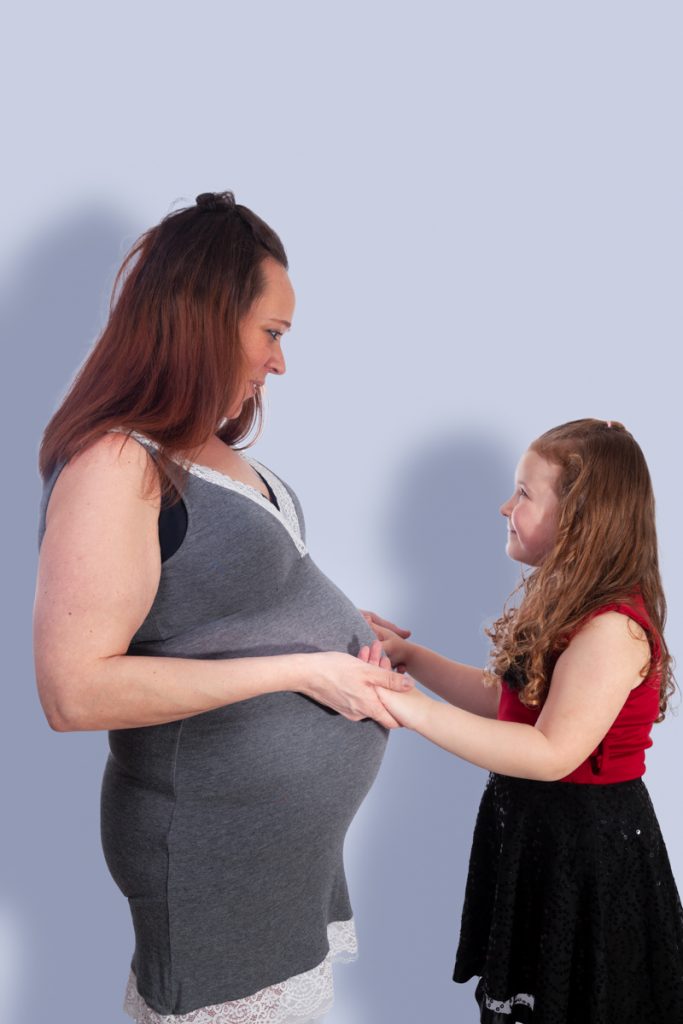 mere et fille en studio l'enfant touche le ventre rond de sa maman