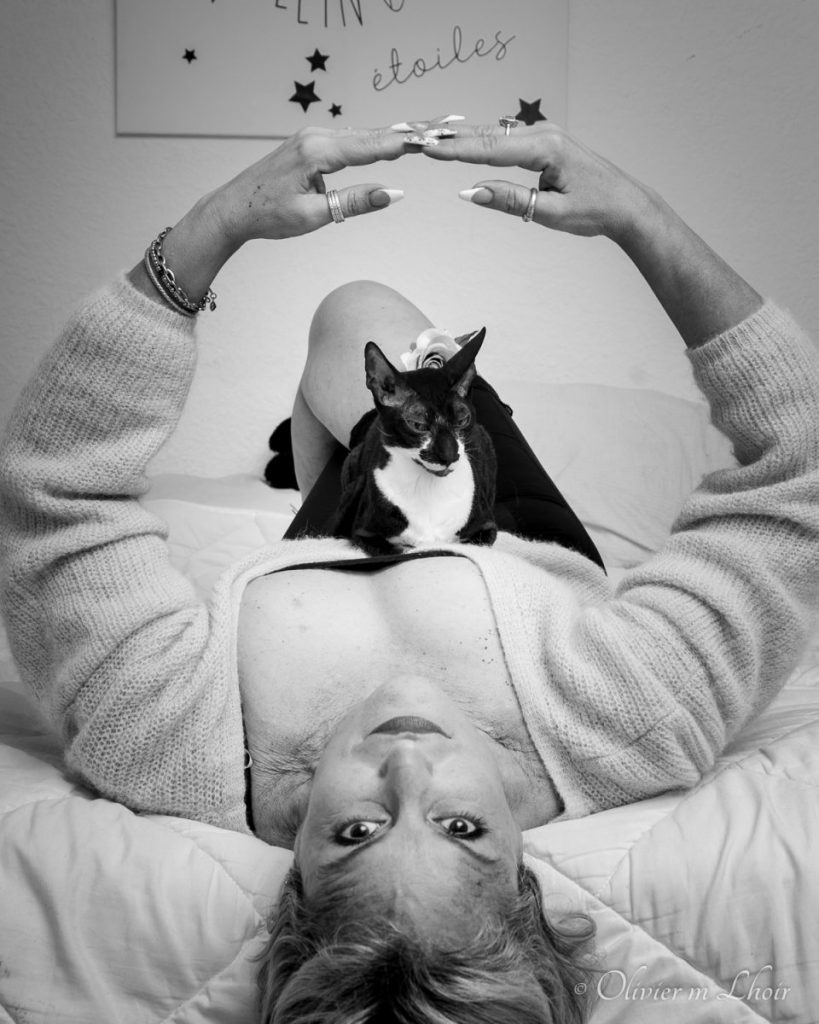 portrait féminin couché sur le dos tête vers l’objectif et un chat sur le ventre noir et blanc
