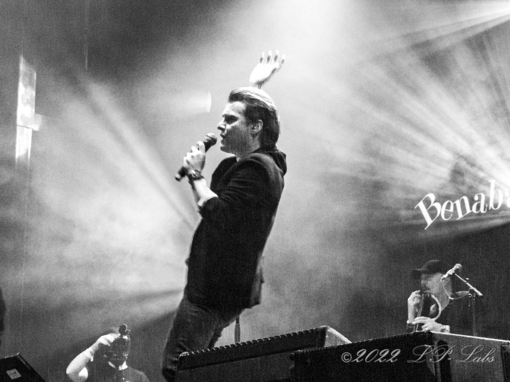 chanteur en noir et blanc saluant la foule sur scene