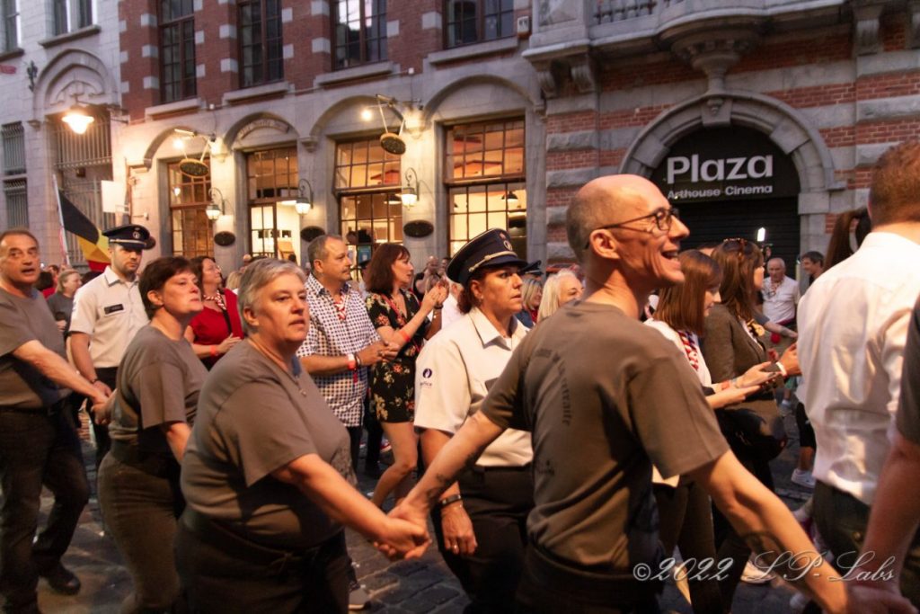 foule animée dans la rue de nuit , parade des flambeaux, entourée d'un cordon de sécurité
